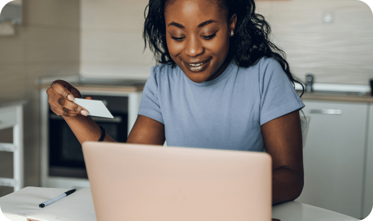 Person using laptop and holding card
